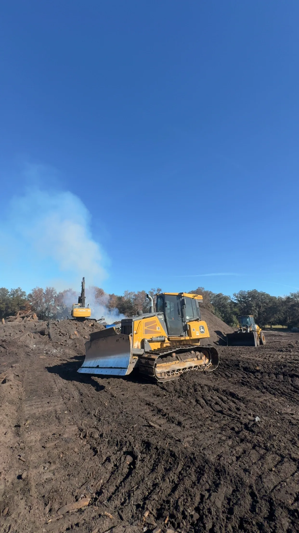 John Deere 700L dozer, wheel loader, and excavator working a land clearing job with a burn pile in Bradford County, Florida
